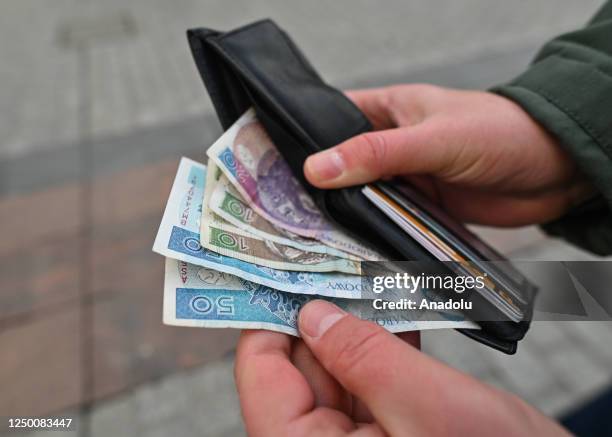 Person takes out Polish Zloty banknotes from a wallet, in Krakow, Poland, on March 28, 2023. In February 2023, Poland experienced a record-breaking...