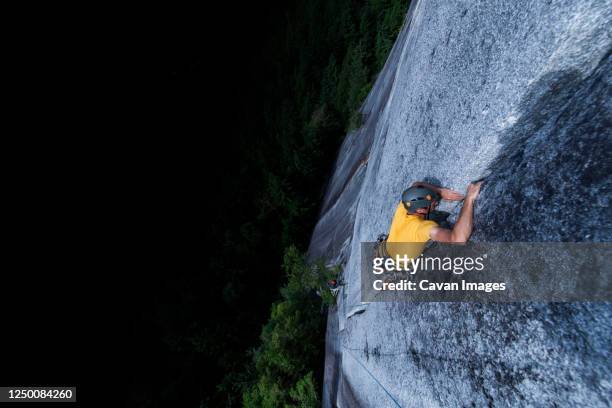 man lead climbing granite crack very high and exposed squamish chief - forward athlete stock pictures, royalty-free photos & images