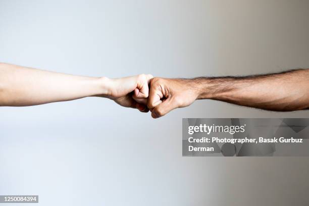 a man and a woman fist bumping - fist bump photos et images de collection