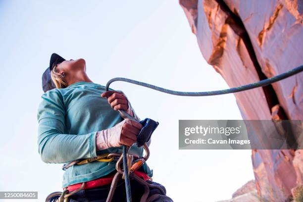 a woman belaying her climbing partner in the desert. - zekeren stockfoto's en -beelden