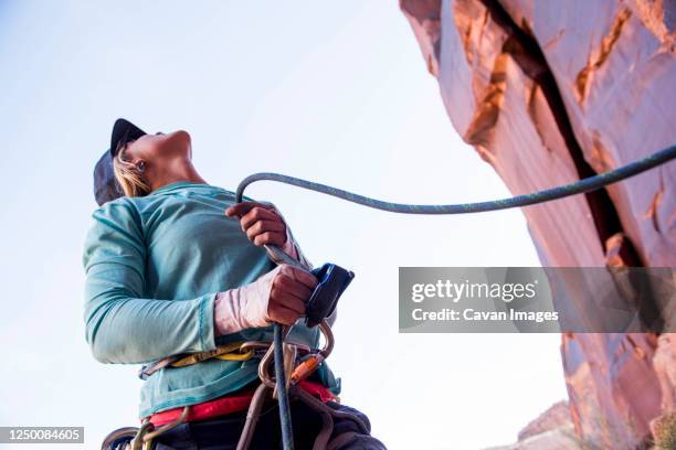 a woman belaying her climbing partner in the desert. - belaying stock pictures, royalty-free photos & images