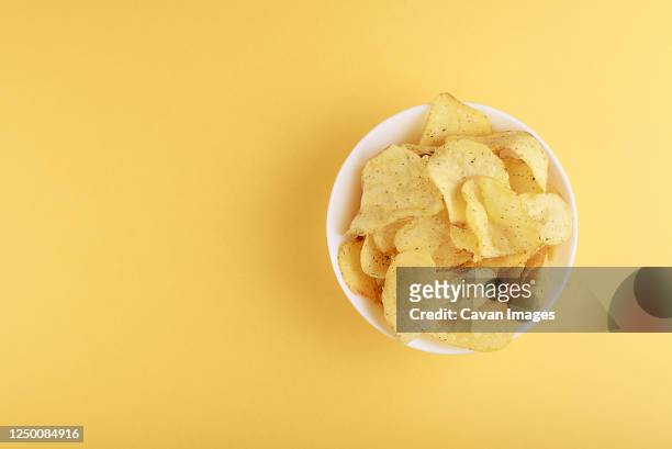 crispy potato chips in bowl on yellow background, top view - american potato farm stockfoto's en -beelden