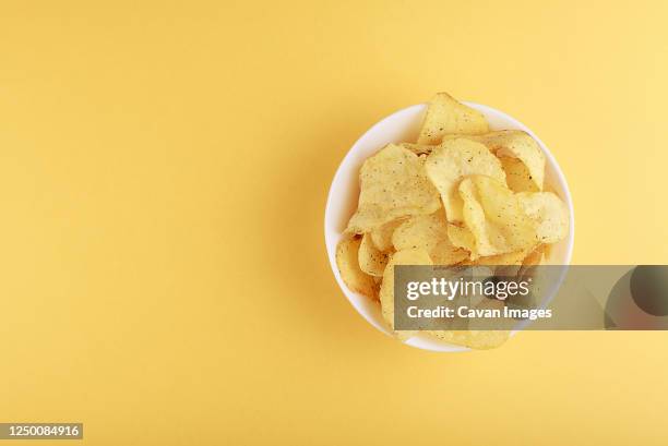 crispy potato chips in bowl on yellow background, top view - potato chips stock pictures, royalty-free photos & images