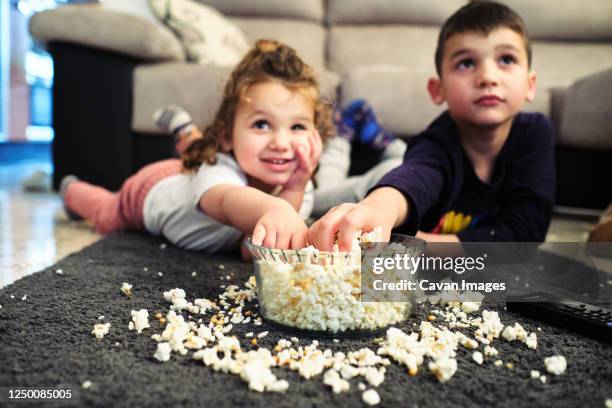 siblings watching a home movie while eating popcorn - movie night stock pictures, royalty-free photos & images