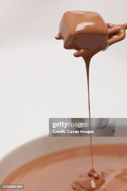 chocolate dripping of praline on white background - caramel liquide photos et images de collection