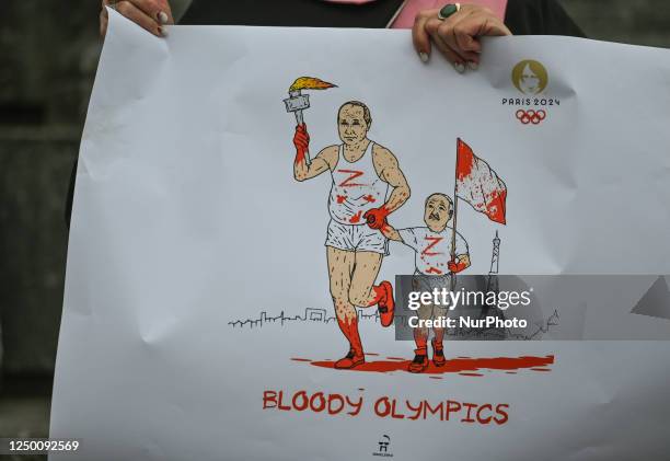 Protester in Krakow holds a powerful poster with Putin and Lukashenko's images, featuring an Olympic torch covered in blood and the words 'Bloody...