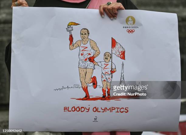 Protester in Krakow holds a powerful poster with Putin and Lukashenko's images, featuring an Olympic torch covered in blood and the words 'Bloody...