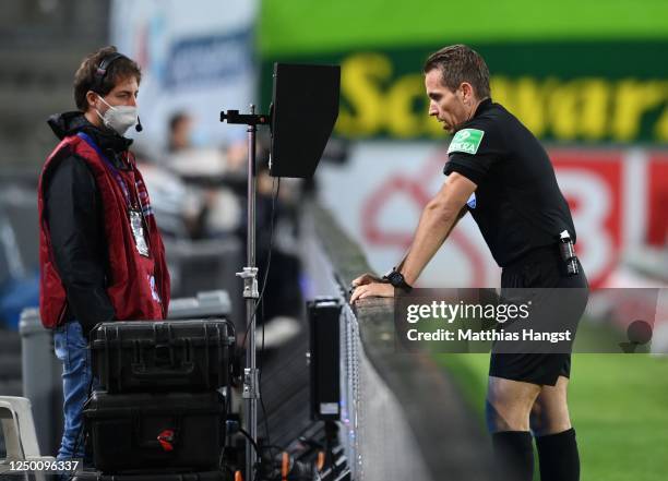 Referee Tobias Stieler of Germany checks the VAR before disallowing a goal during the Bundesliga match between Sport-Club Freiburg and Hertha BSC at...