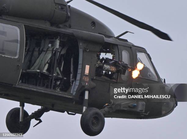 Serviceman shoots from a Black Hawk helicopter during a demonstration as part of the rotation of US troops of the US Army 101 Airborne division at...