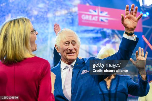 March 2023, Hamburg: King Charles III of Great Britain, waves next to Jill Gallard , British Ambassador to Germany, on stage at the ceremonial...