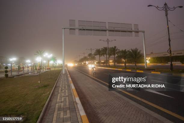 Vehicles drive down a road in Baghdad as thick dust blankets the city, on March 31, 2023. - A sandstorm enveloped central Iraq, including Baghdad on...