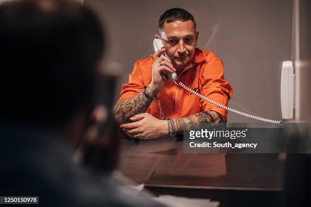 male inmate talking with his lawyer in prison visit room - prisoner phone stock pictures, royalty-free photos & images