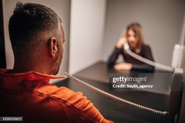 male prisoner talking with his sad wife in prison visit room - prisoner visit stock pictures, royalty-free photos & images