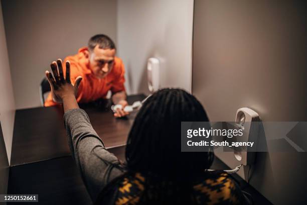 male prisoner talking with his sad wife in prison visit room - prisoner visit stock pictures, royalty-free photos & images