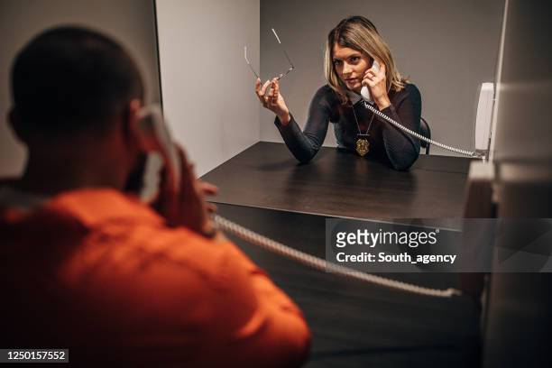 gevangene die met vrouwelijke detective in gevangenisbezoekruimte spreekt - jail room stockfoto's en -beelden