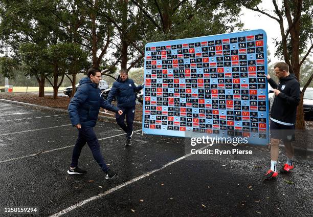 Alex Wilkinson of Sydney FC helps to move the media backdrop before the media conference during a Sydney FC A-League training session at Macquarie...