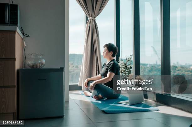 une séance d’entraînement asiatique chinoise belle femme à la maison médiation sur le tapis de yoga au coin de cuisine près de la fenêtre le matin week-end - salle yoga photos et images de collection