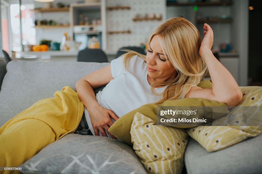 Woman with hands on stomach suffering from pain stock photo