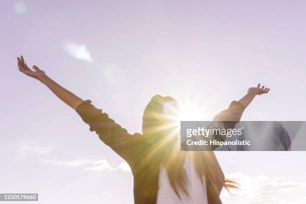 腕を開けて屋外で太陽の光を楽しむ幸せな女性 - 覚悟 ストックフォトと画像