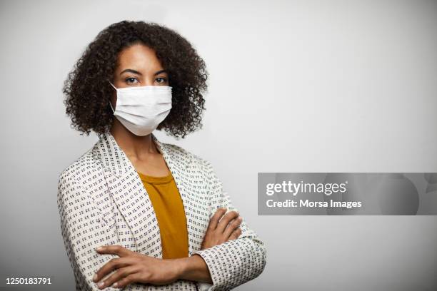 portrait of young african american female with arms crossed wearing n95 face mask. - businesswoman mask stock pictures, royalty-free photos & images