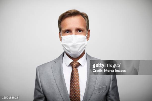 portrait of confident male leader wearing n95 face mask and gray suit. - male portrait suit and tie stock-fotos und bilder