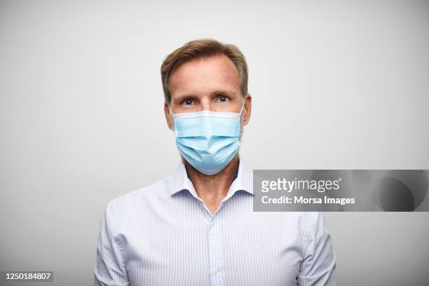 handsome mid adult businessman with surgical mask. - face mask protective workwear imagens e fotografias de stock