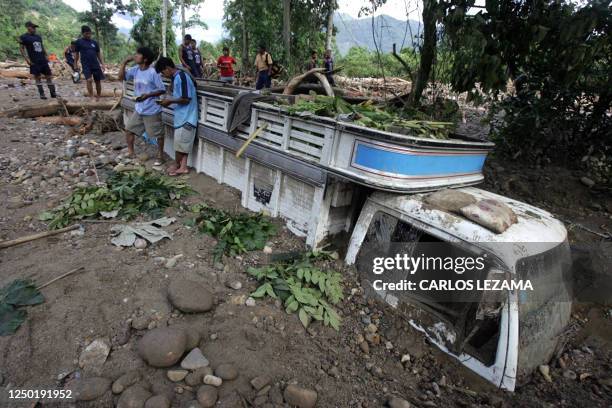People stay around a truck partially covered by mud by a landslide 23 January 2007 in Chanchamayo, 350 km east from Lima. At least 16 people died and...
