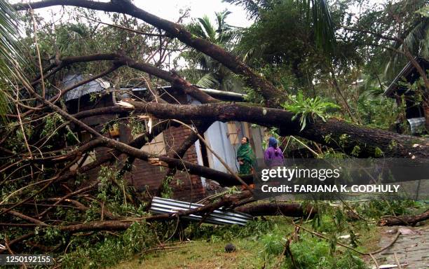 Bangladeshi women look at the devestation caused when a huge tree fell on their house during the cyclone in Mongla in Khulna, some 320 kilometers...