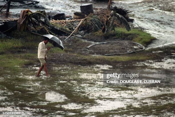 Lone Villager with an umbrella walks through torrential rain past cyclone-destroyed hutments 03 May 1991 in Anwara, Chittagong district. On the night...