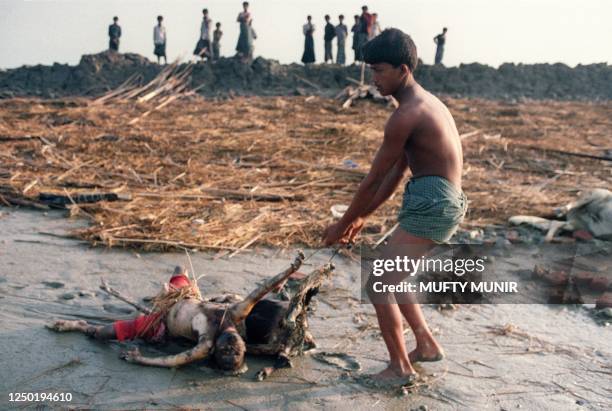 Man removes bodies of cyclone victims for burial 04 May 1991 past cyclone-destroyed hutments 04 May 1991 on Kutubida Island near Chittagong. On the...