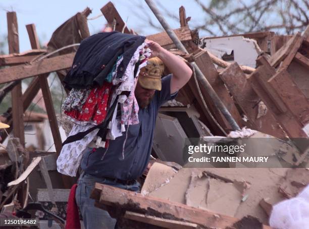 Man carries clothes from a house that was destroyed by tornados in Moore, OK 05 May 1999, two days after several tornadoes ripped through Oklahoma...