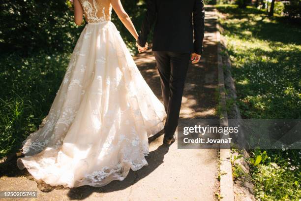 bride and groom walking on pavements - kanten jurk stockfoto's en -beelden