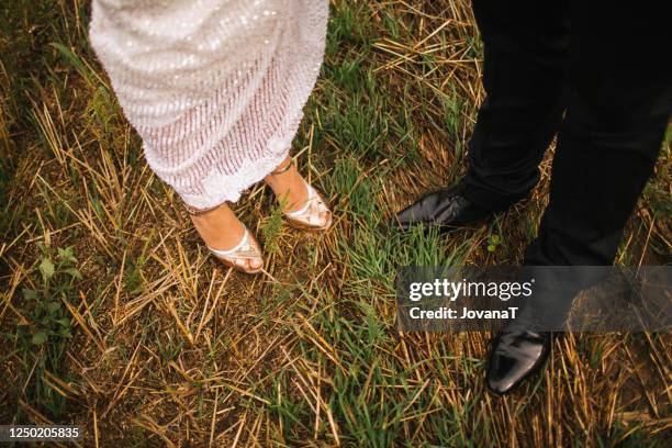 bride and groom in a muddy field - high heel stockfoto's en -beelden