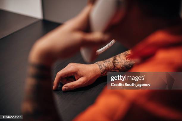 male prisoner talking on phone in prison visit room - prisoner phone stock pictures, royalty-free photos & images