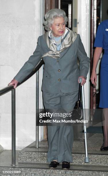 Queen Elizabeth II, seen wearing trousers and using a crutch, leaves the King Edward VII Hospital after undergoing knee surgery on January 14, 2003...