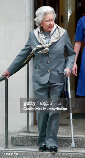 Queen Elizabeth II, seen wearing trousers and using a crutch, leaves the King Edward VII Hospital after undergoing knee surgery on January 14, 2003...
