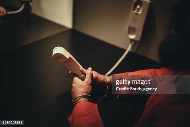 mannelijke gevangene die telefoon in gevangenisbezoekruimte houdt - jail room stockfoto's en -beelden