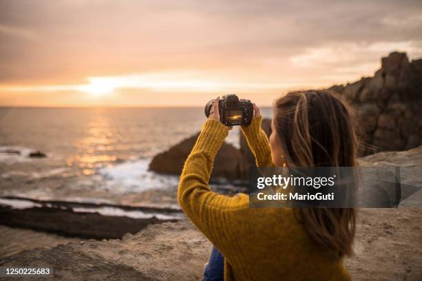 junge frau mit einer dslr-kamera in einem schönen küstengebiet - spiegelreflexkamera stock-fotos und bilder