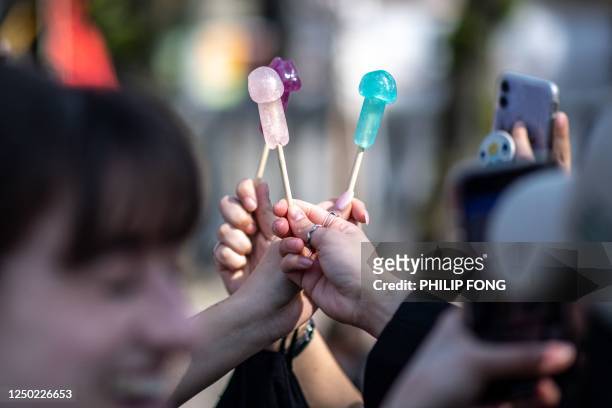 Visitors take pictures of phallus-shaped candy ahead of the Kanamara festival at the Kanayama shrine in Kawasaki on April 1, 2023. -