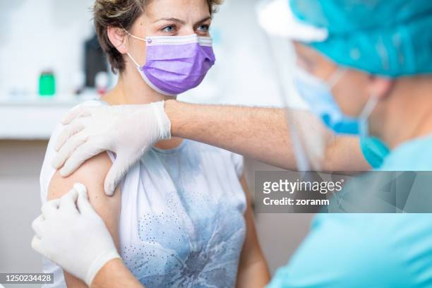 female patient's arm disinfected with cotton pad for vaccination - serbia covid stock pictures, royalty-free photos & images