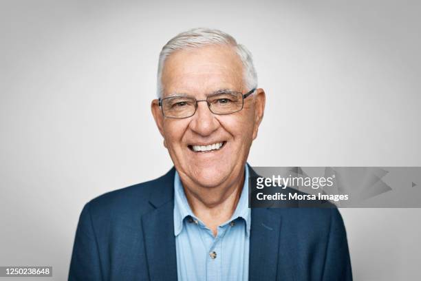 smiling senior businessman on white background - portrait stock-fotos und bilder