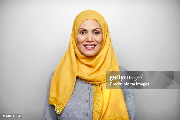 portrait of smiling mid adult woman wearing hijab. - arabia stock-fotos und bilder