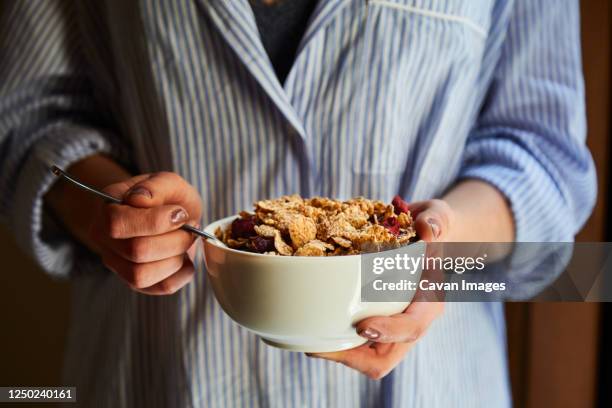 young woman having breakfast next to a window at home - muesli fotografías e imágenes de stock