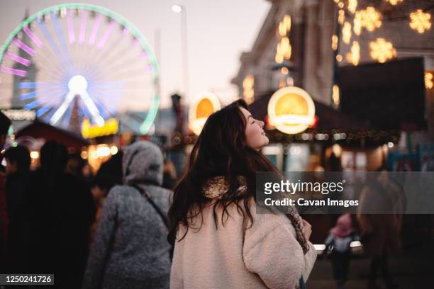 happy teenage girl enjoying city while walking in christmas market - mid adult women photos et images de collection