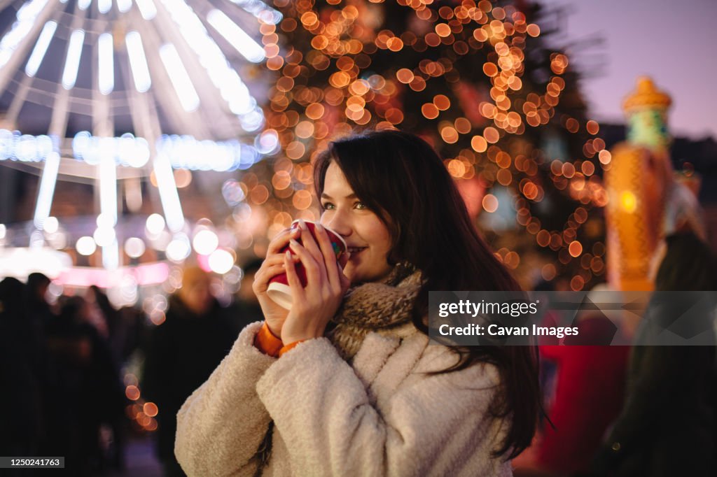 Happy teenage girl drinking mulled wine in Christmas market