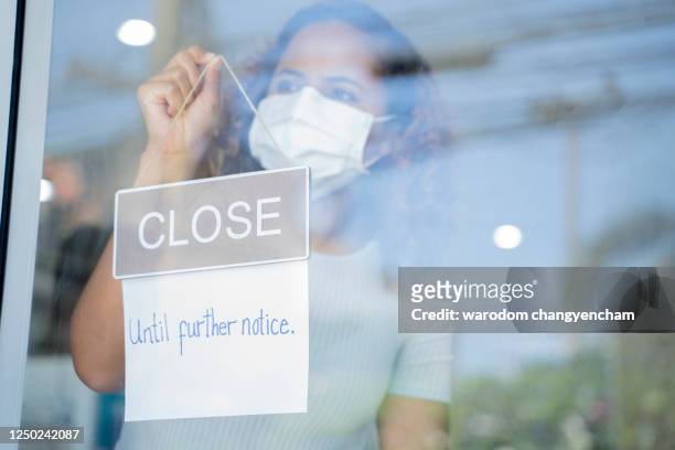 woman holding "closed until further notice" sign. - closed until further notice stock pictures, royalty-free photos & images