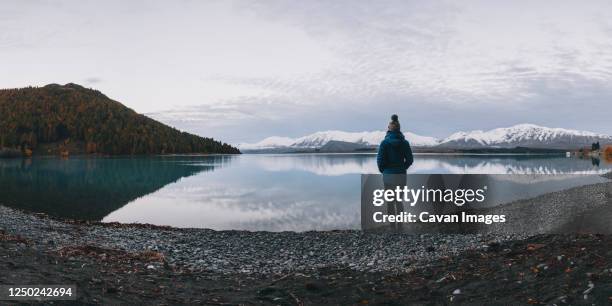 young woman stands in front of lake tekapo and the southern alps - lake tekapo ストックフォトと画像