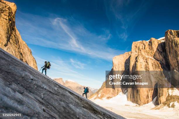 backpackers hiking up glacier, ascending mount asgard, baffin island. - steep stock pictures, royalty-free photos & images