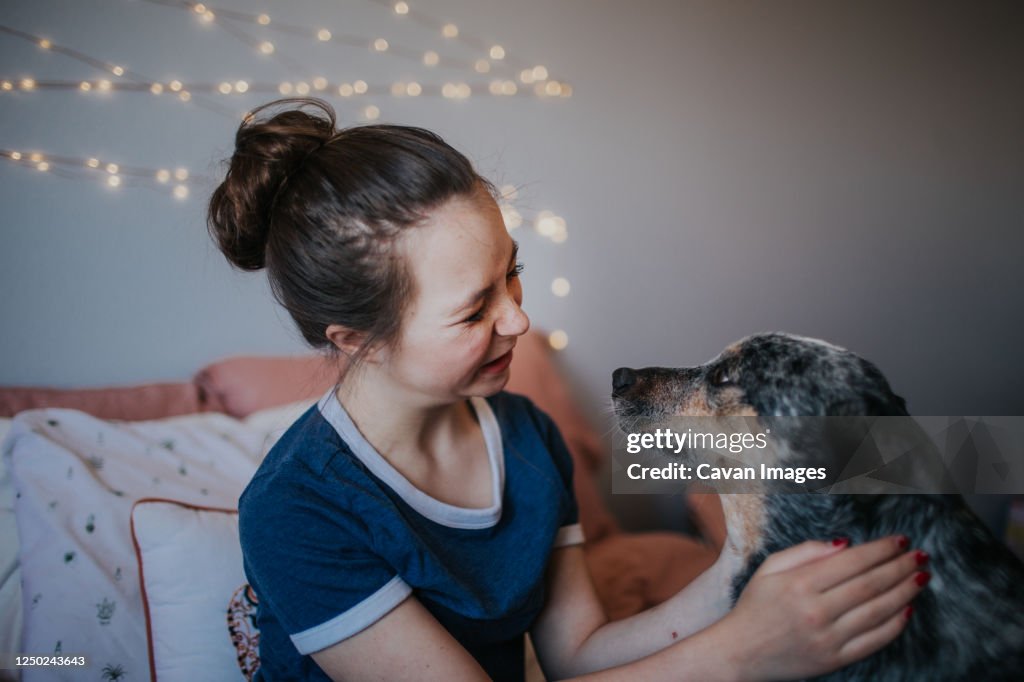 Tween girl playing with her dog on her bed