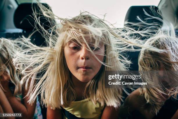 boys and girls in backseat of car with hair blowing in wind - car kids stock-fotos und bilder